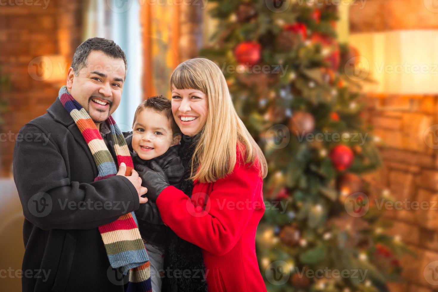 Young Mixed Race Family Portrait In Front of Christmas Tree Indoors. photo