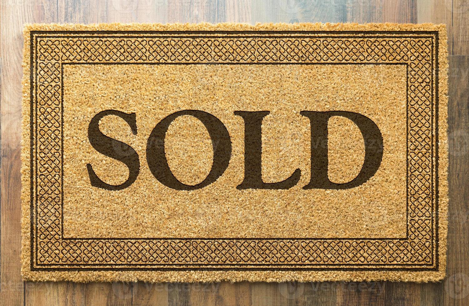 Sold Welcome Mat On A Wood Floor Background photo