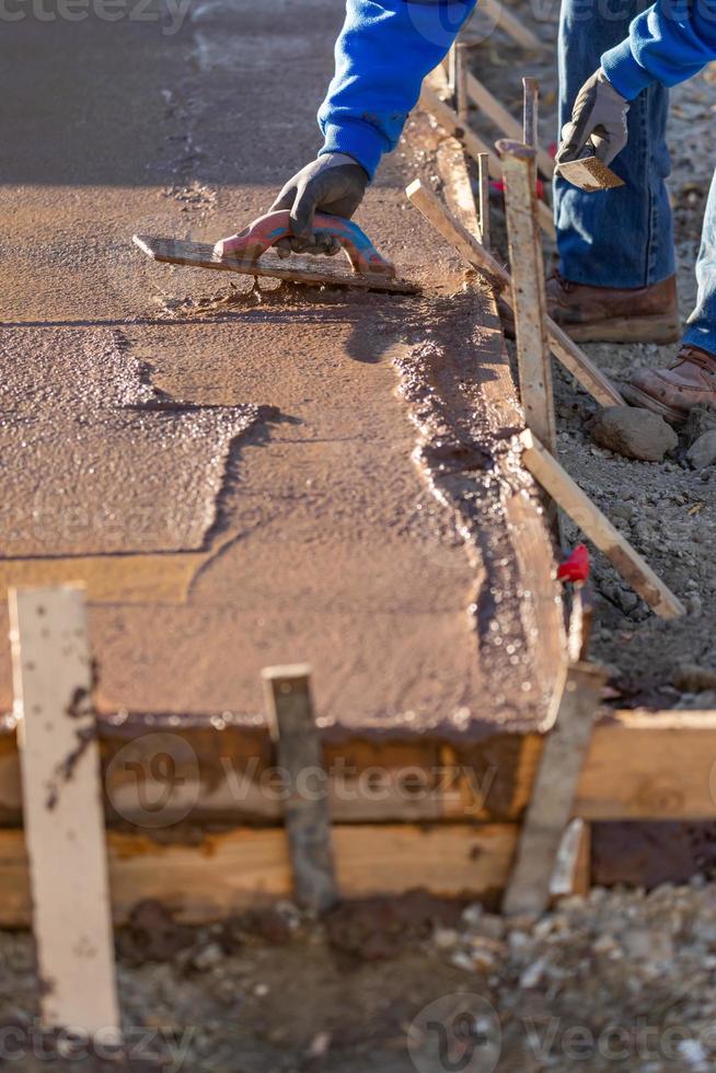 trabajador de la construcción alisando cemento húmedo con herramientas de paleta foto