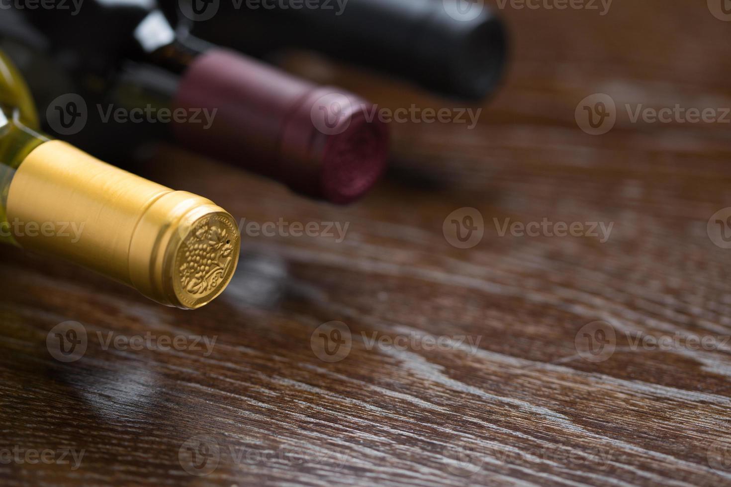 varias botellas de vino en un resumen de superficie de madera reflectante. foto