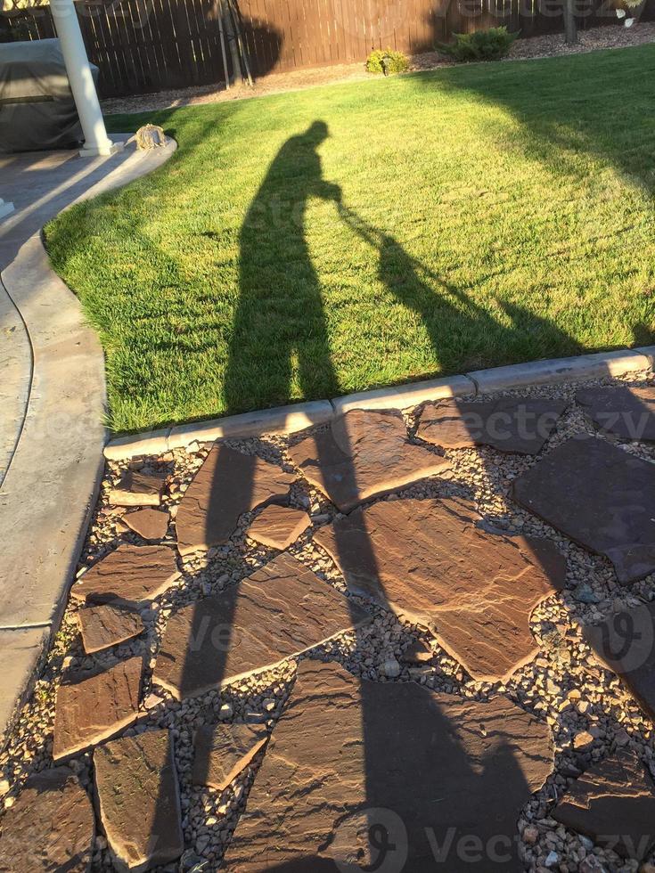 Shadow of Man Pushing Lawn Mower Over Grass photo