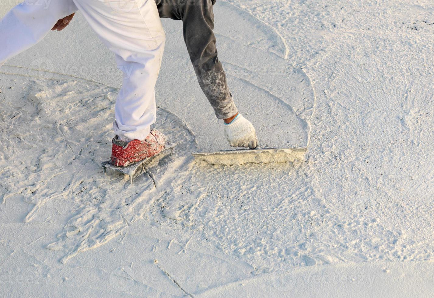 Worker Wearing Spiked Shoes Smoothing Wet Pool Plaster With Trowel photo