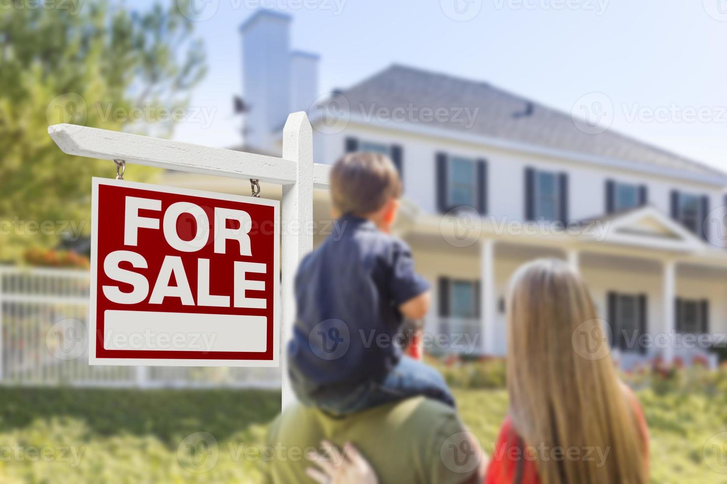 Family Facing For Sale Real Estate Sign and House photo