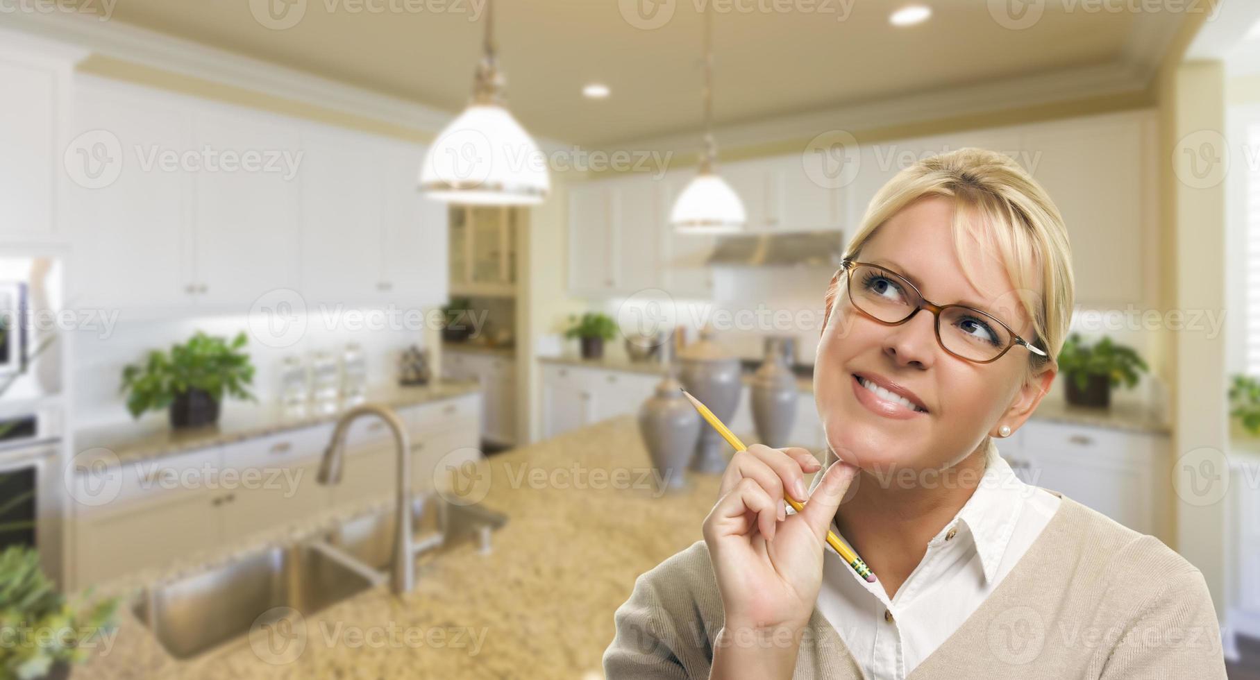 Daydreaming Woman with Pencil Inside Beautiful Kitchen photo