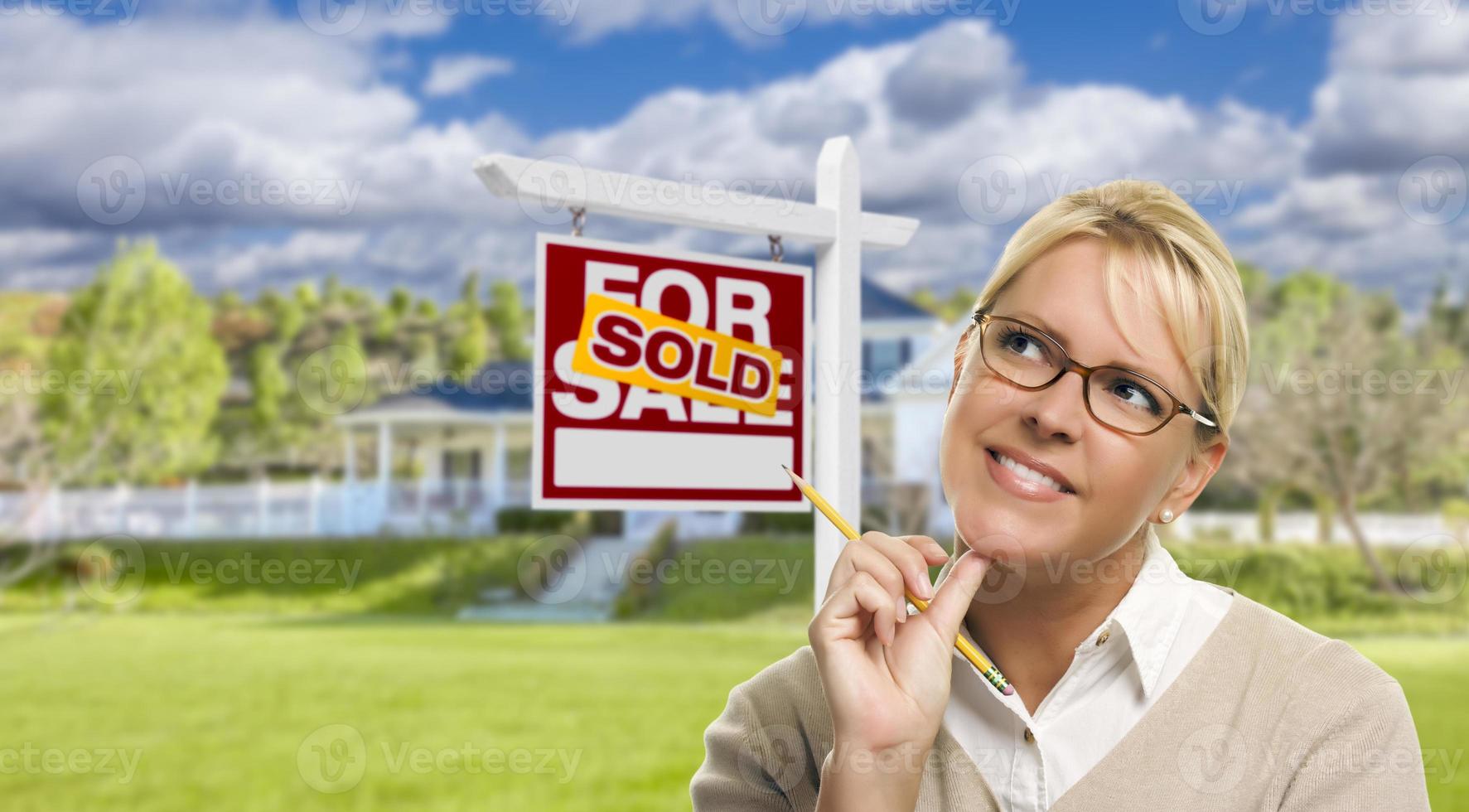 Young Woman in Front of Sold Sign and House photo