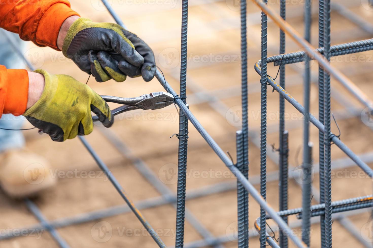 Worker Securing Steel Rebar Framing With Wire Plier Cutter Tool At Construction Site photo