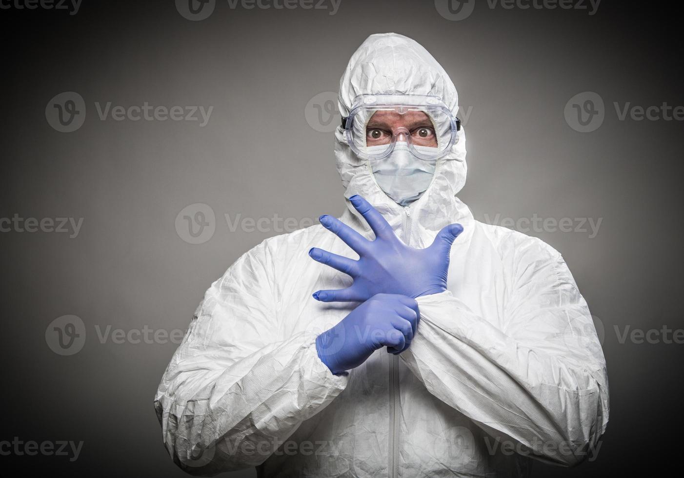 hombre con expresión intensa usando ropa protectora contra materiales peligrosos contra un fondo gris. foto