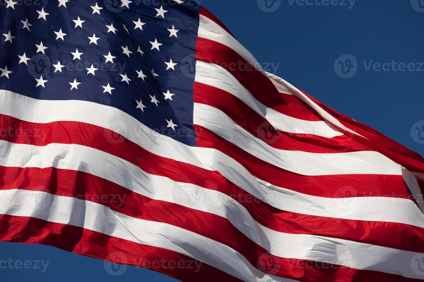 American Flag Waving In Wind Against a Deep Blue Sky photo