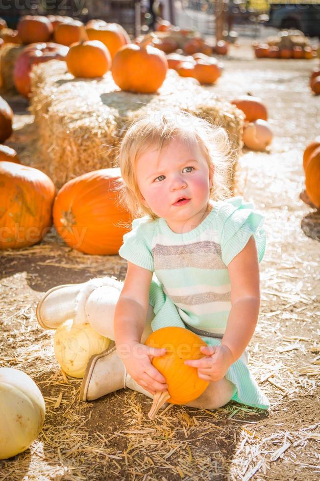 adorable niña divirtiéndose en un rancho rústico en el huerto de calabazas. foto