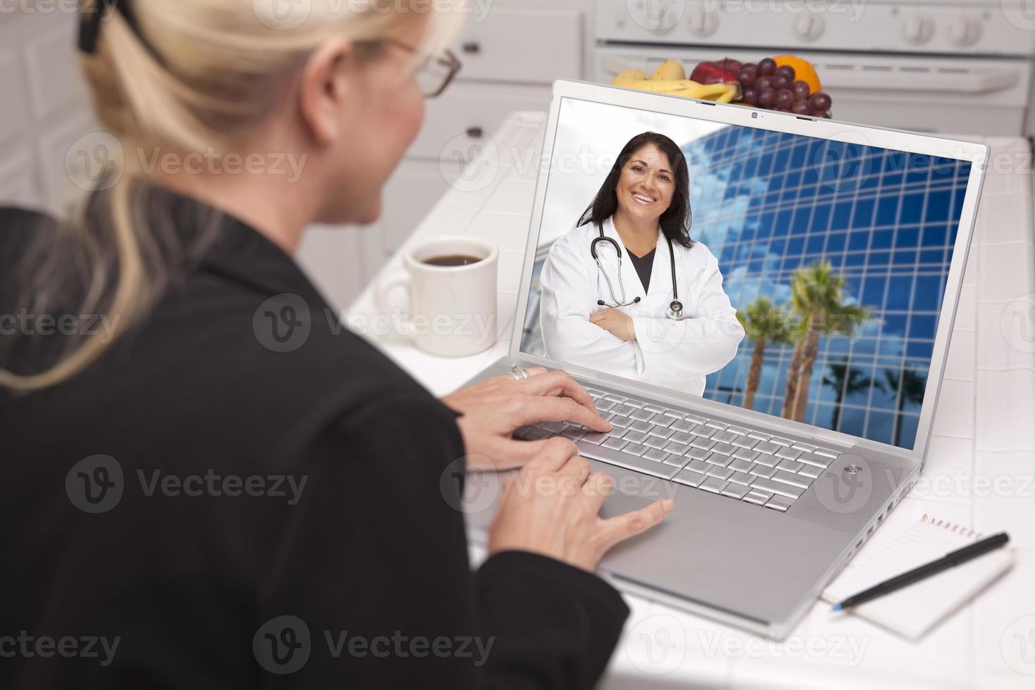 Woman In Kitchen Using Laptop - Online with Nurse or Doctor photo