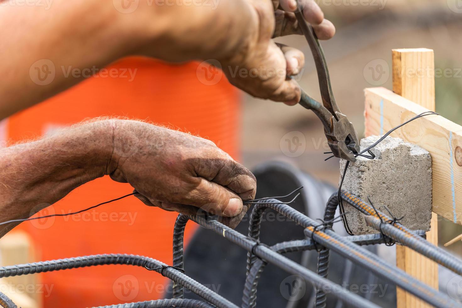 Trabajador que asegura la estructura de barras de refuerzo de acero con la herramienta de corte de alicates de alambre en el sitio de construcción foto