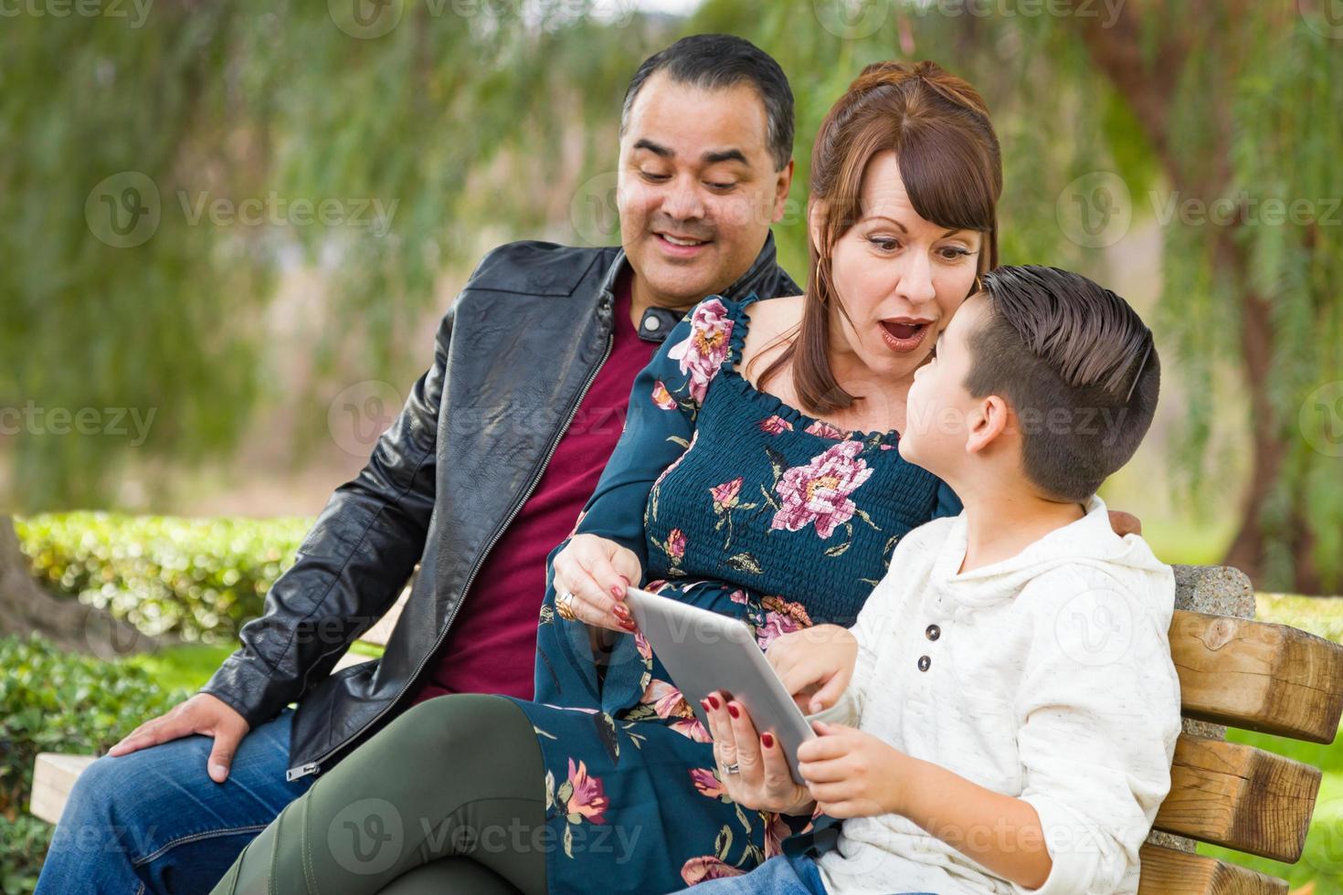Caucasian Mother and Hispanic Father Using Computer Tablet With Mixed Race Son Outdoors photo