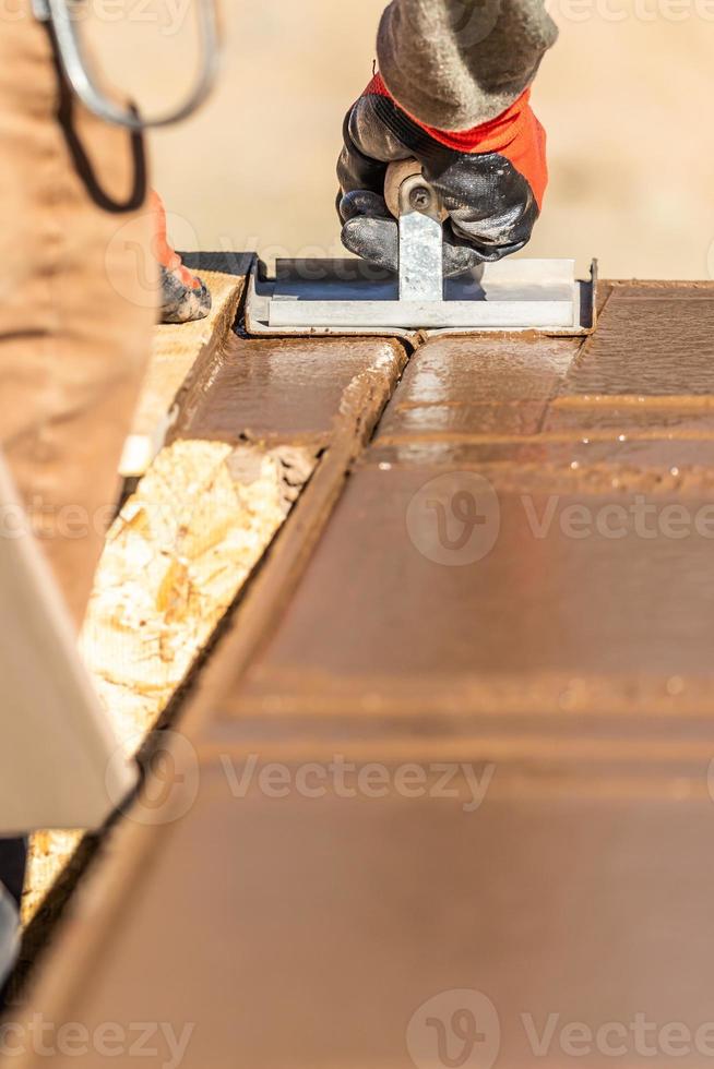 Construction Worker Using Hand Groover On Wet Cement Forming Coping Around New Pool photo