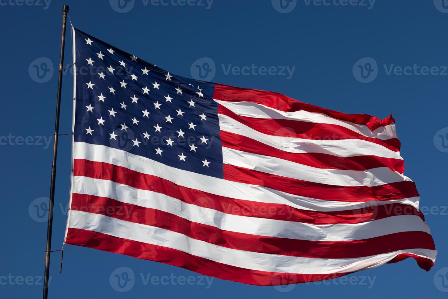 American Flag Waving In Wind Against a Deep Blue Sky photo