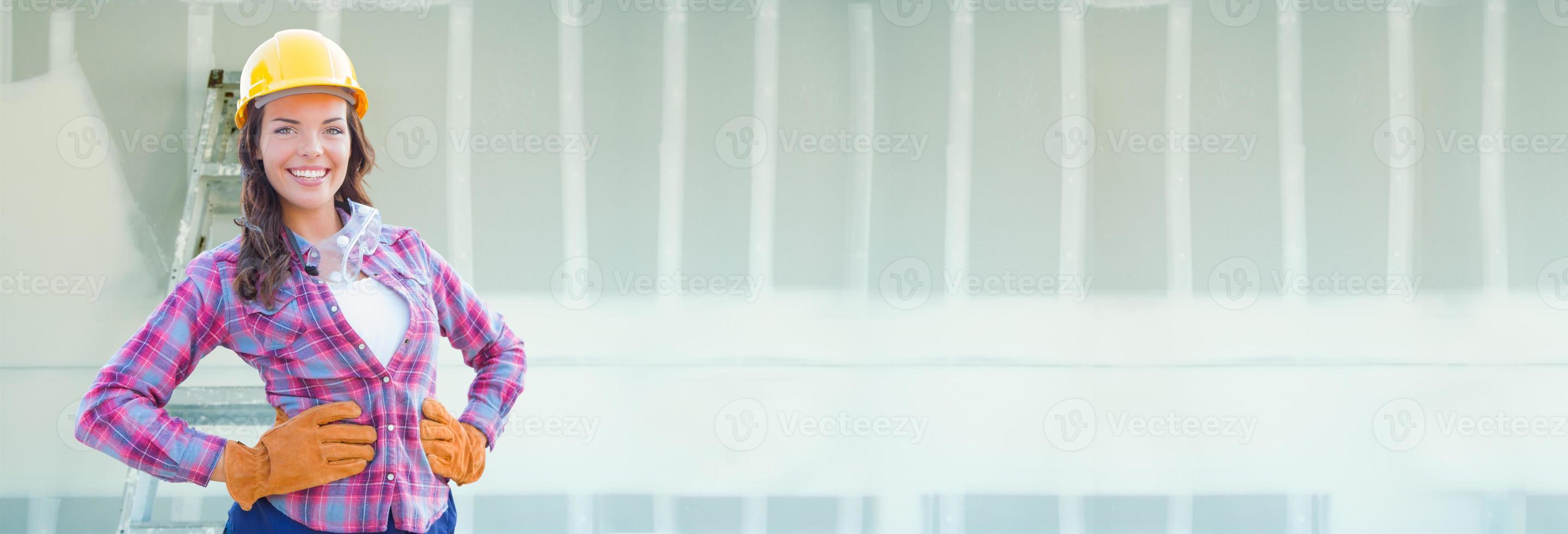 Female Contractor Wearing Hard Hat Against Dywall Banner Background with Ladder photo