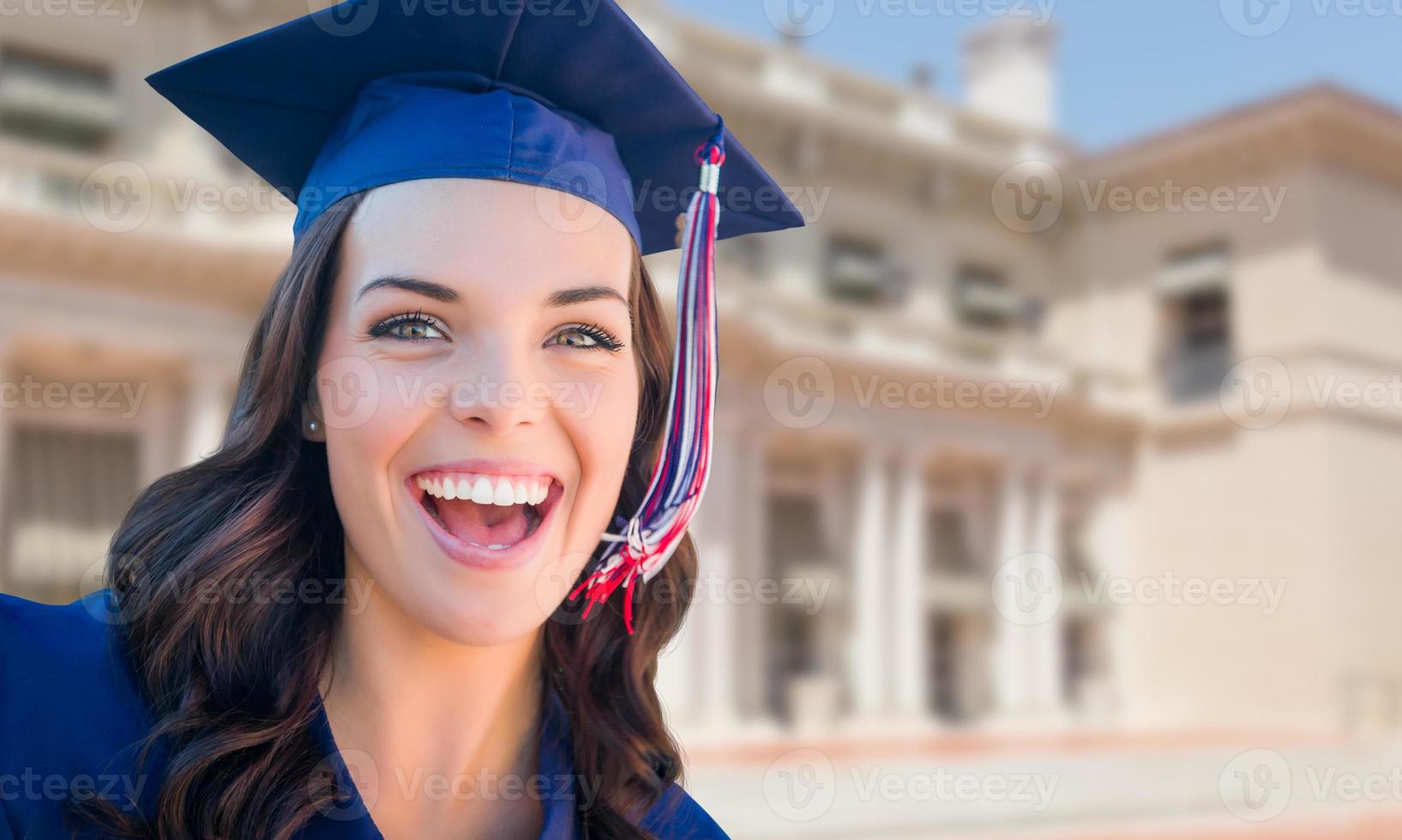 feliz graduada mujer de raza mixta en toga y birrete celebrando en el campus. foto