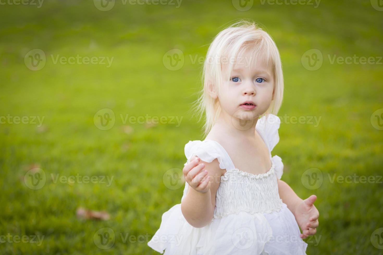 Adorable Little Girl Wearing White Dress In A Grass Field photo