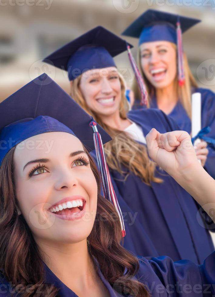 Happy Graduating Group of Girls In Cap and Gown Celebrating on Campus. photo