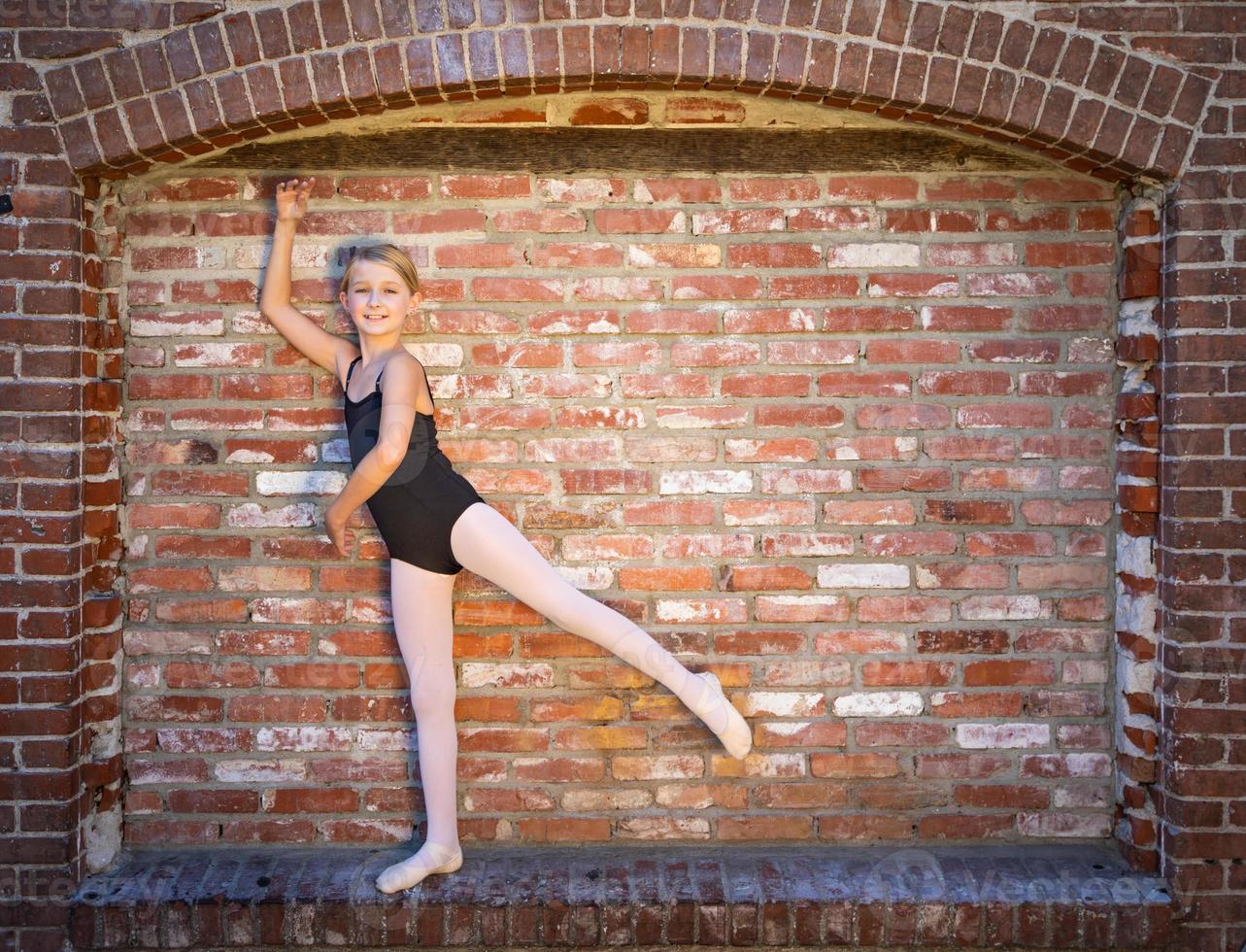 Cute Caucasian Ballerina Girl Posting Against A Brick Wall photo