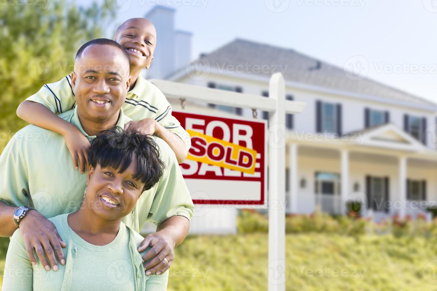 familia afroamericana frente al letrero vendido y la casa foto