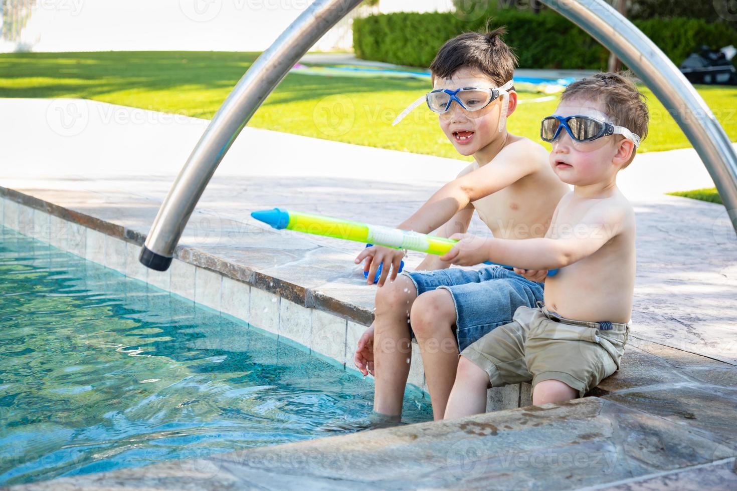 Young Mixed Race Chinese and Caucasian Brothers Wearing Swimming Goggles Playing At The Pool photo