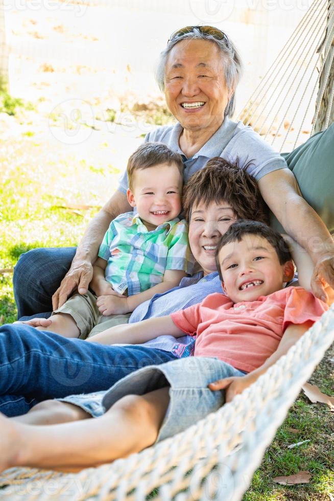 Chinese Grandparents In Hammock with Mixed Race Children photo