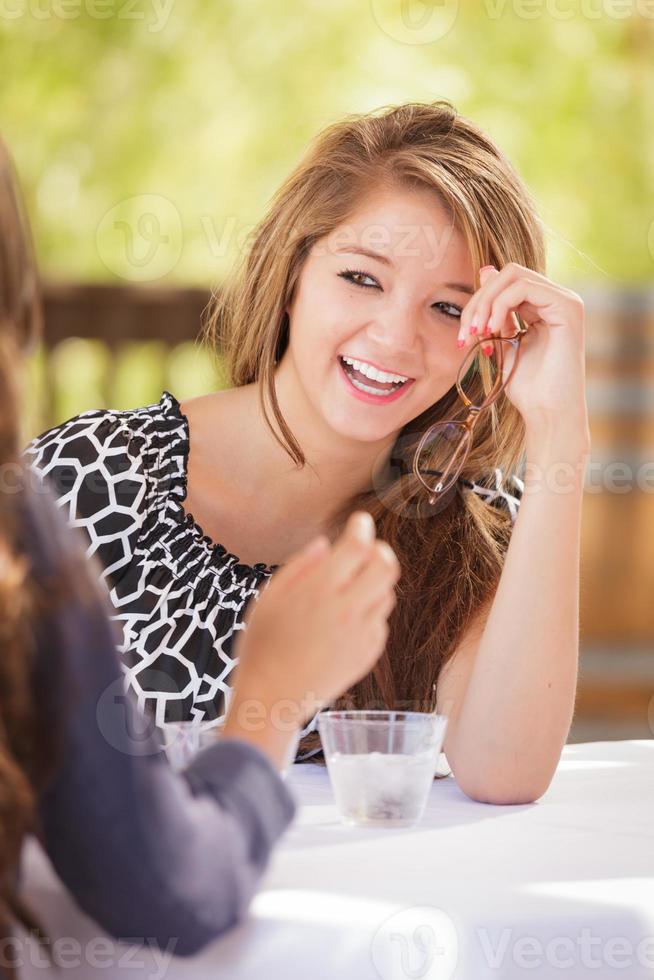 Two Mixed Race Girlfriends Talking Over Drinks Outdoors photo