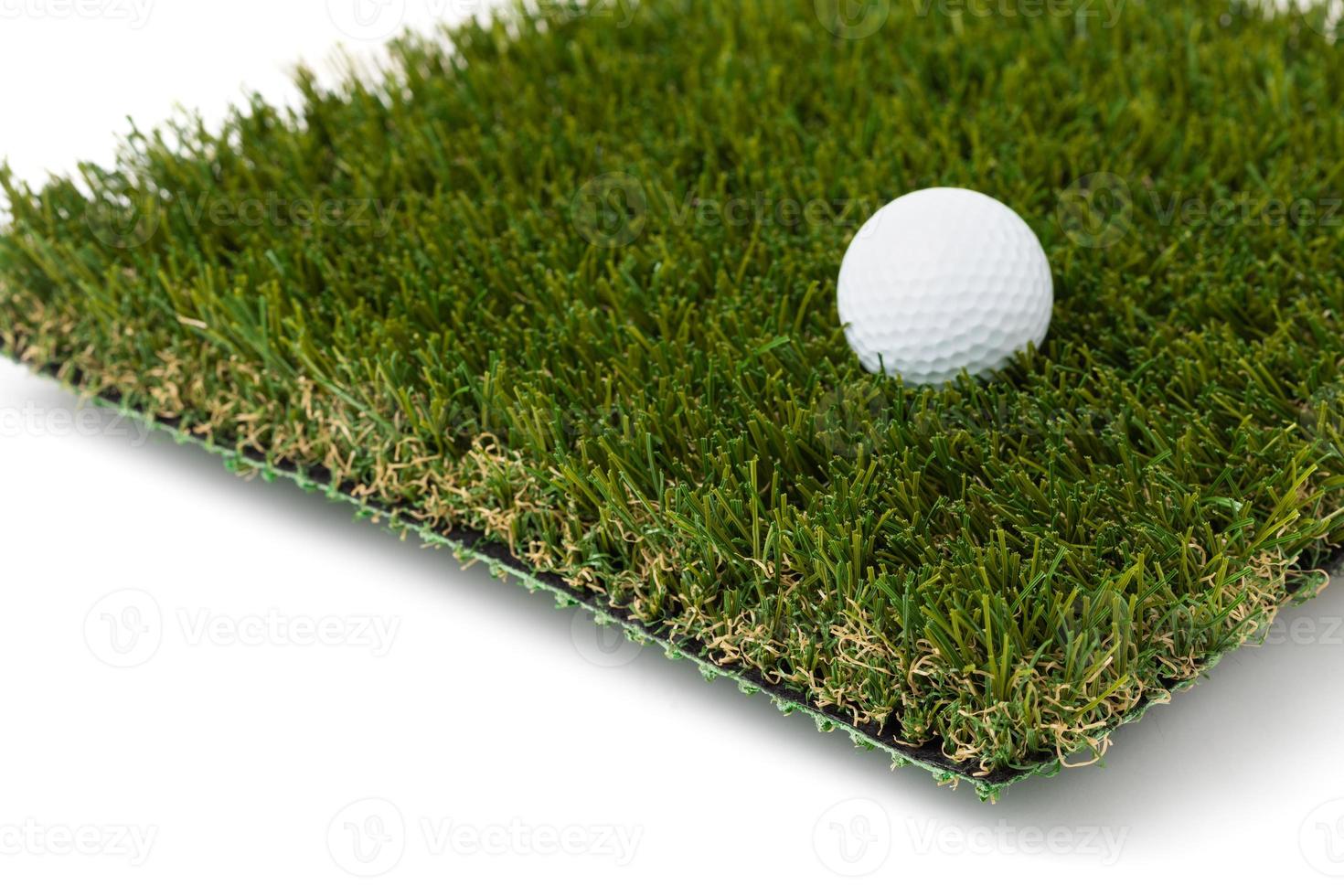 pelota de golf descansando sobre una sección de césped artificial sobre fondo blanco foto