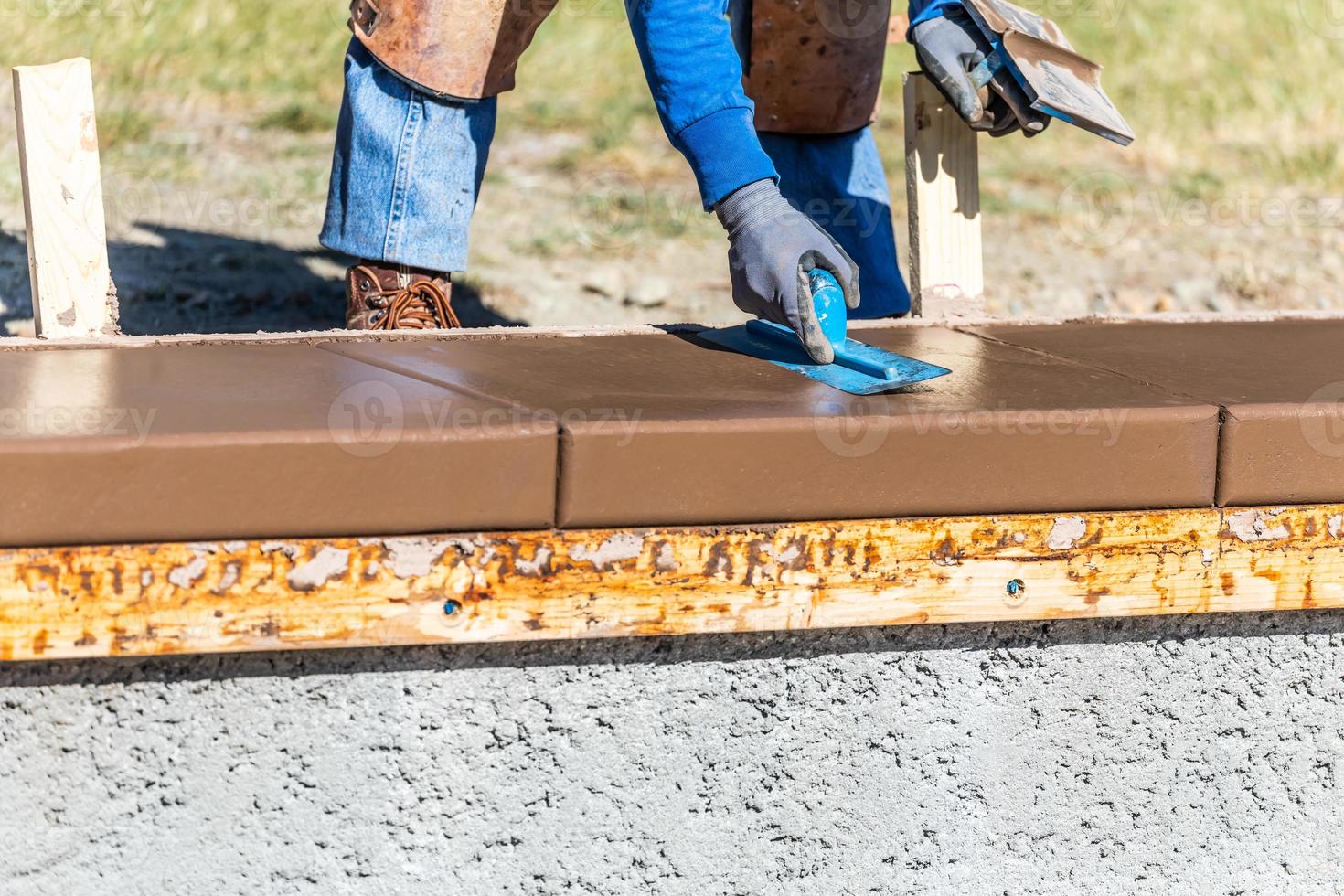 trabajador de la construcción usando paleta sobre cemento húmedo formando afrontamiento alrededor de la nueva piscina foto