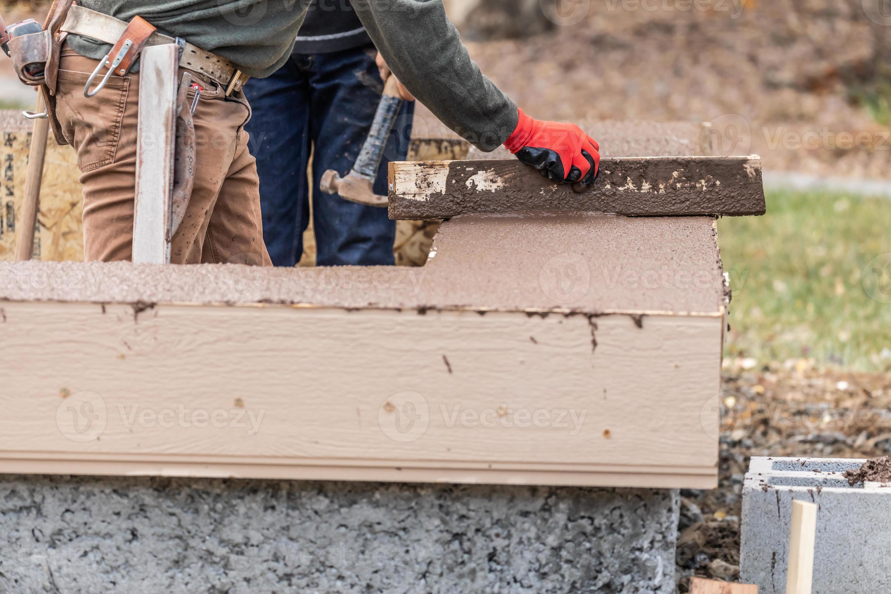 Construction Worker Leveling Wet Cement Into Wood Framing 16444632