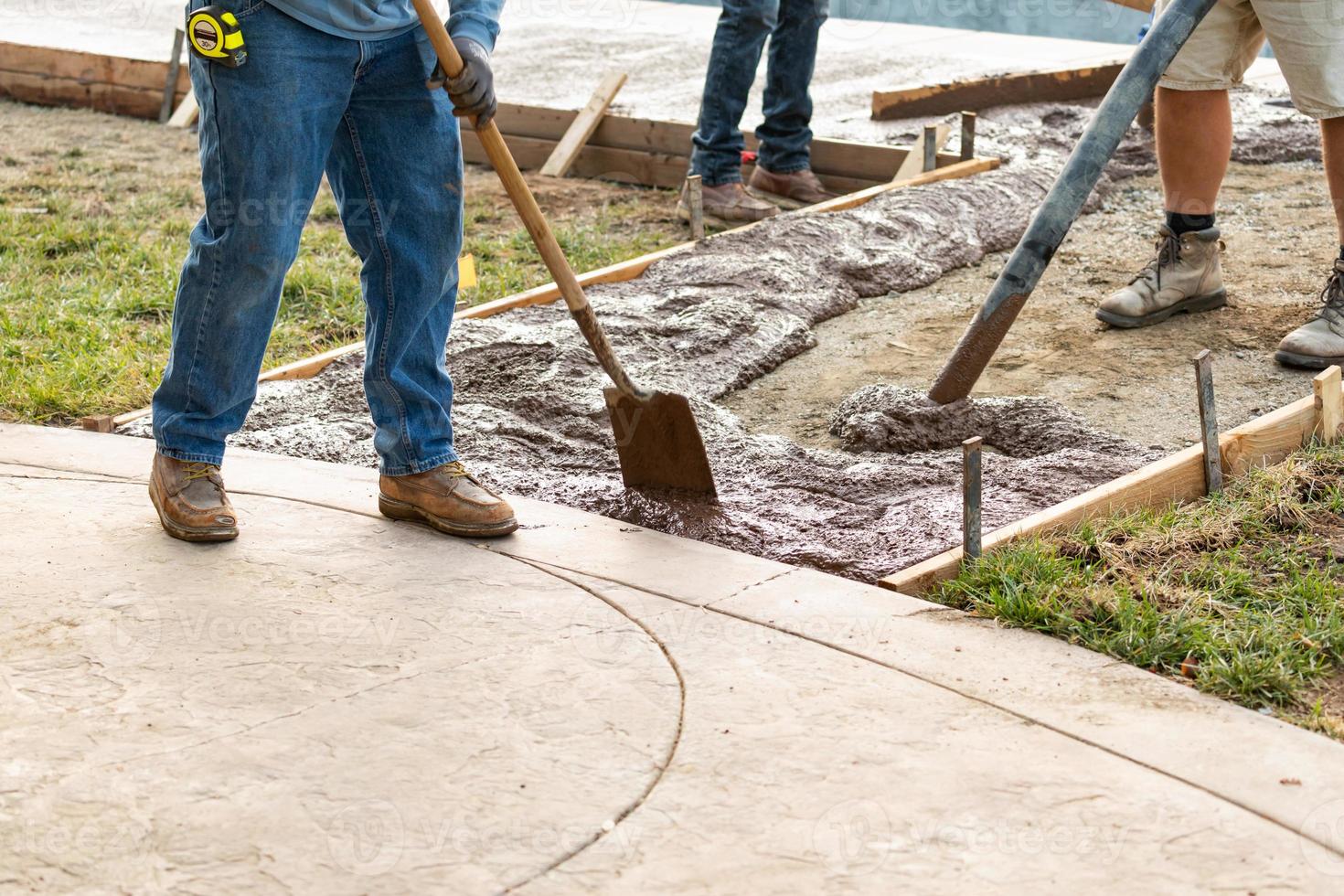 Construction Worker Pouring Wet Deck Cement Into Wooden Frame photo