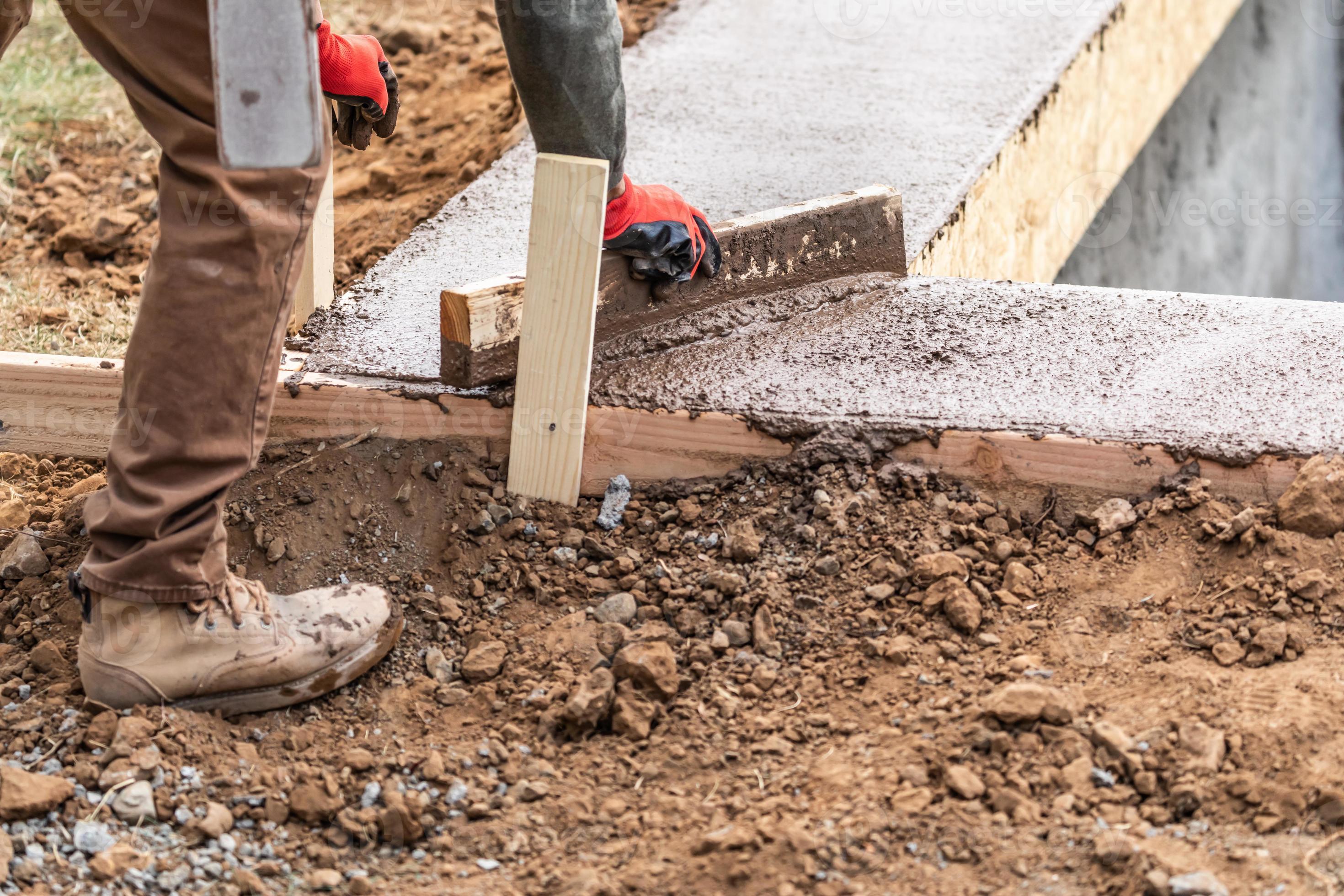 Construction Worker Leveling Wet Cement Into Wood Framing 16444676