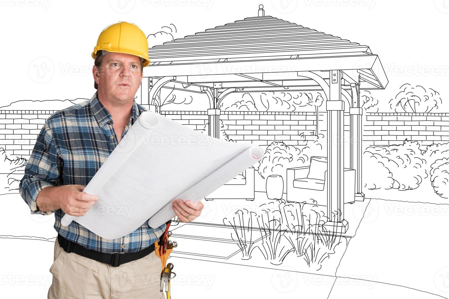 Male Contractor With House Plans Wearing Hard Hat In Front of Custom Pergola Patio Covering Drawing photo