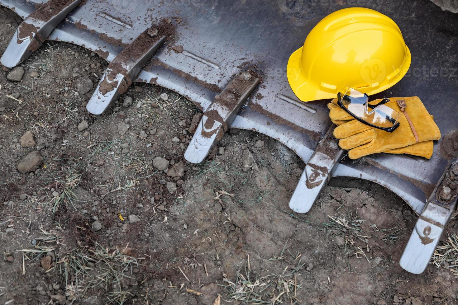 Hardhat, Gloves and Protective Glasses Resting on Bulldozer Bucket Abstract photo