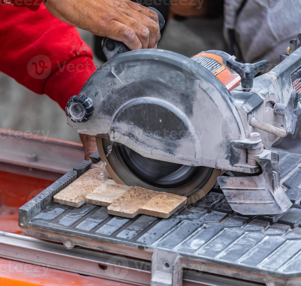 Worker Using Wet Tile Saw to Cut Wall Tile At Construction Site
