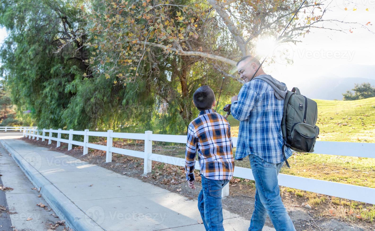 Mixed Race Father And Son Outdoors Walking With Fishing Poles photo