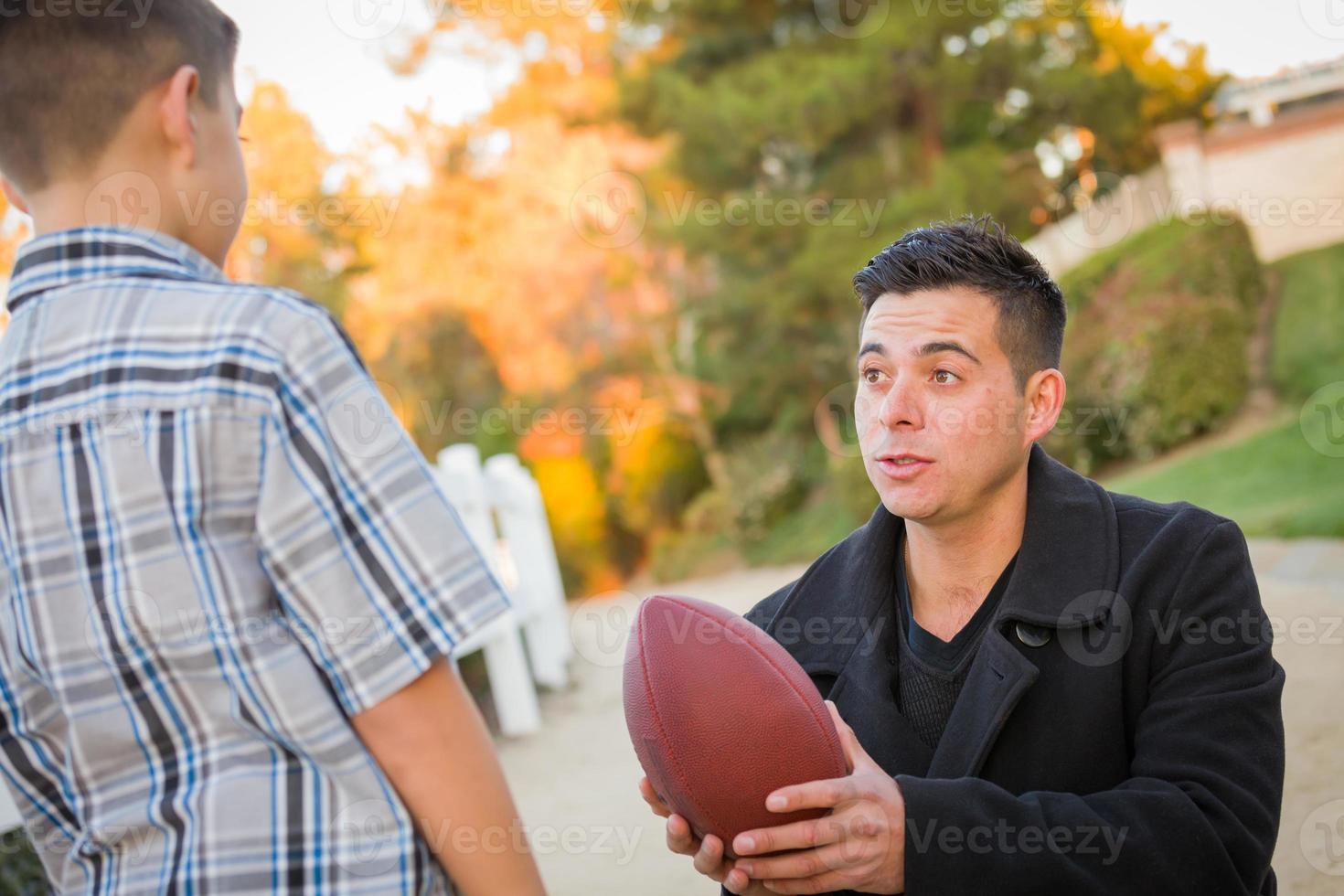 Hispanic Father Holding Football Teaching Young Boy photo