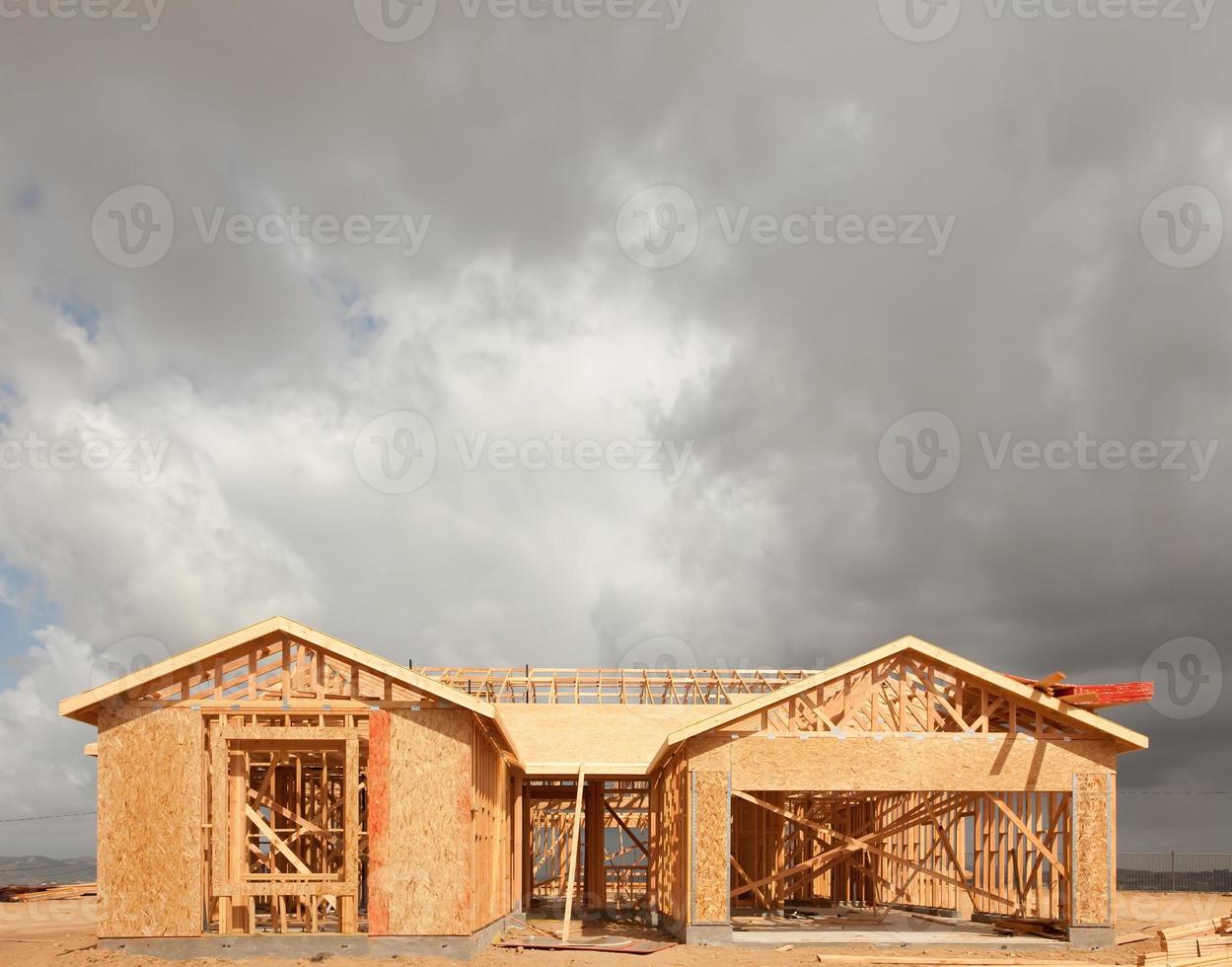 Casa de madera enmarcando resumen en el sitio de construcción con nubes tormentosas detrás foto