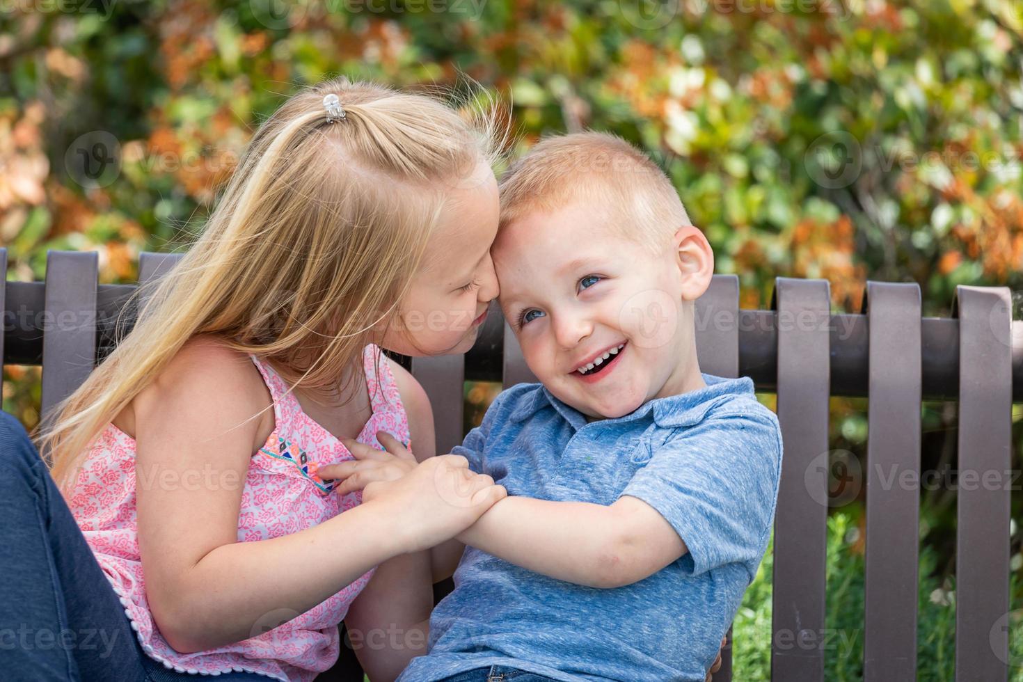 Young Sister and Brother Having Fun On The Bench At The Park photo
