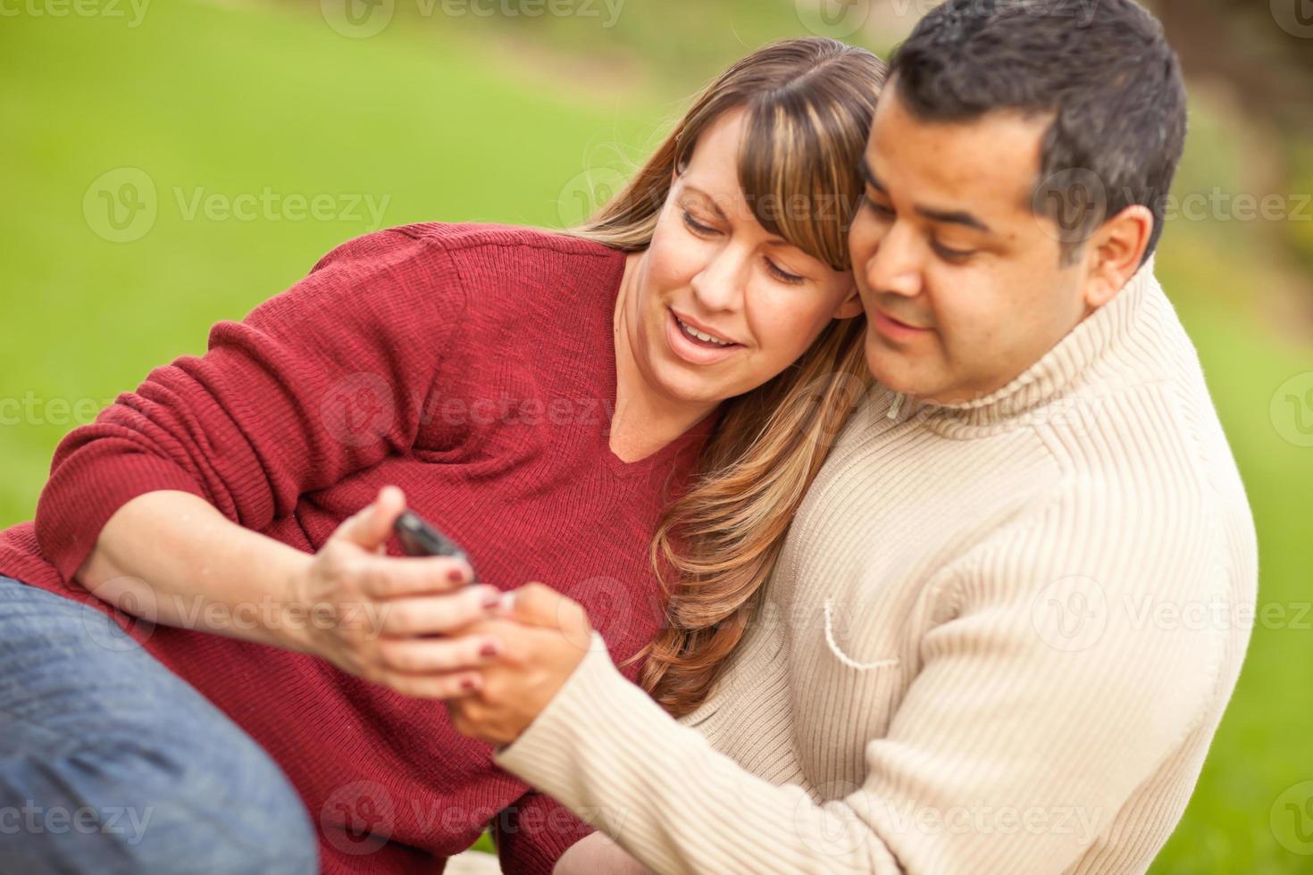 Attractive Mixed Race Couple Enjoying Their Camera Phone in the Park photo
