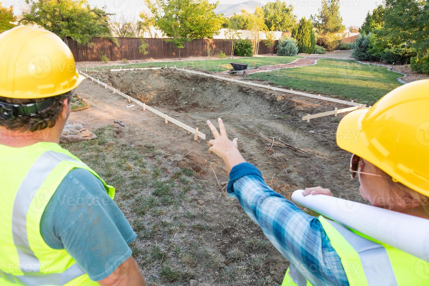 Male and Female Workers Overlooking Pool Construction Site photo