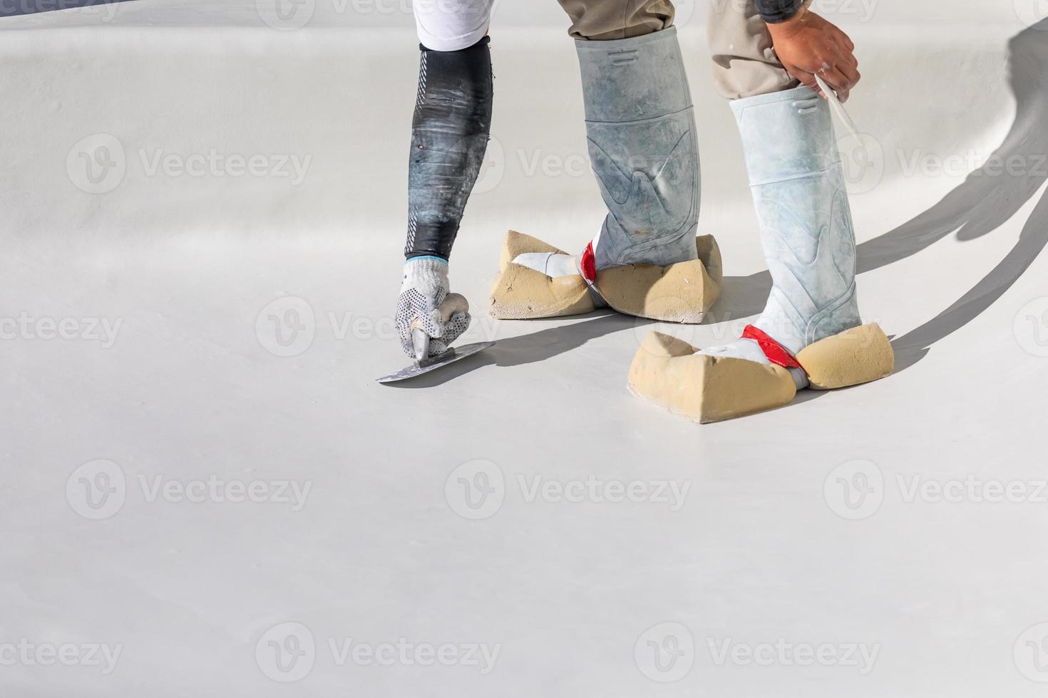 Worker Wearing Sponges On Shoes Smoothing Wet Pool Plaster With Trowel photo