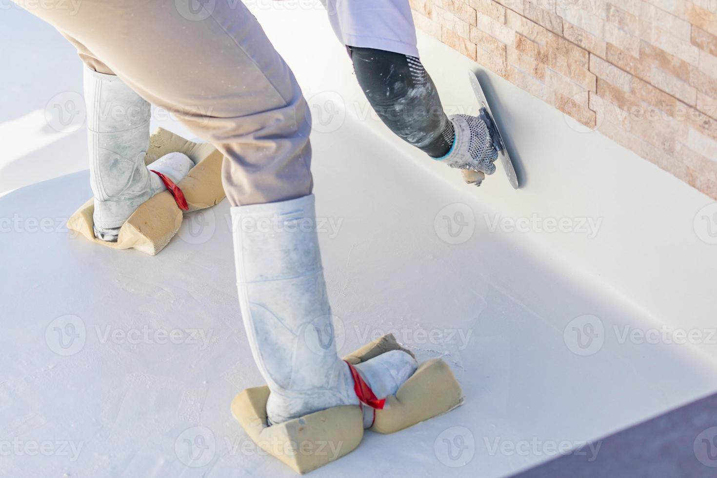 Worker Wearing Sponges On Shoes Smoothing Wet Pool Plaster With Trowel photo