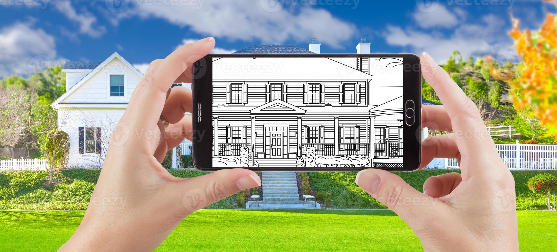Hands Holding Smart Phone Displaying Drawing of Home Photo Behind