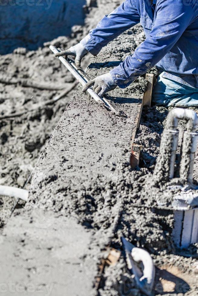 trabajador de la construcción de piscinas que trabaja con una varilla más suave en hormigón húmedo foto