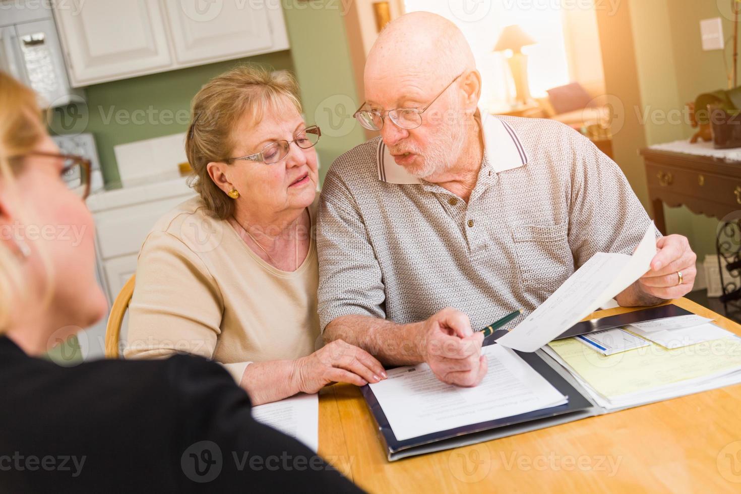 Senior Adult Couple Going Over Documents in Their Home with Agent At Signing photo