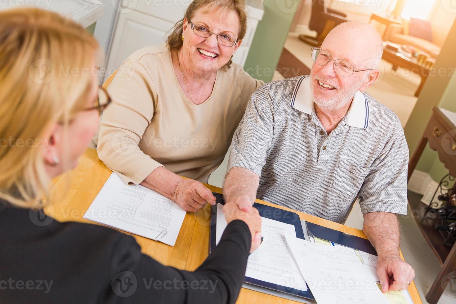 Senior Adult Couple Going Over Documents in Their Home with Agent At Signing photo