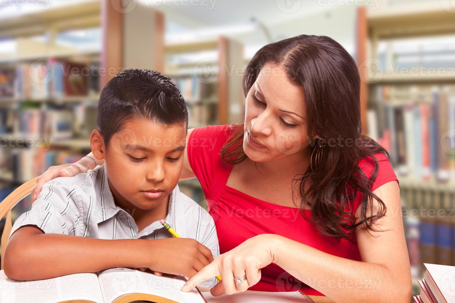 joven hispano y adulto famle estudiando en la biblioteca foto