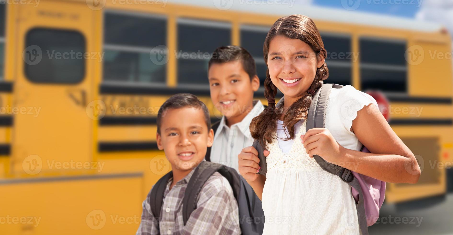 jóvenes hispanos niñas y niños caminando cerca del autobús escolar foto
