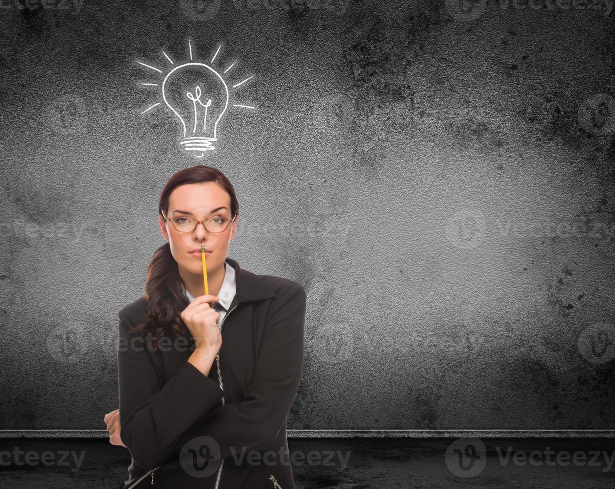 Light Bulb Drawn Above Head of Young Adult Woman With Pencil In Front of Wall with Copy Space photo